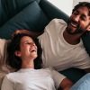 two people laughing on a couch